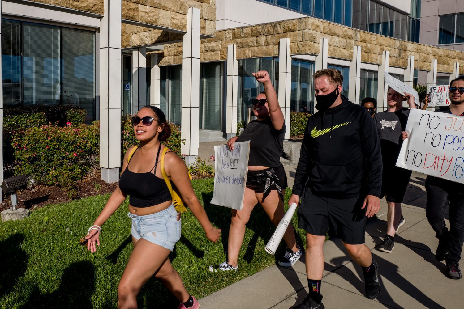 Young people, one with her first in the air, march past the police station at 400 Mare Island Way in Vallejo, Calif.