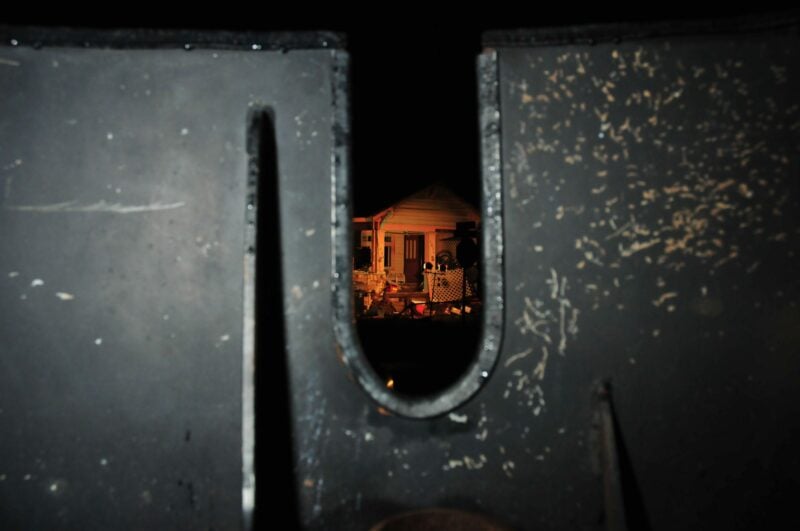 A house seen through a police vehicle turret at night