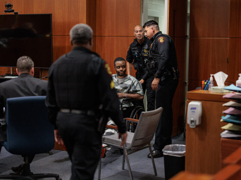 A young Black man is wheeled into a courtroom while surrounded by Solano County Sheriff's deputies.