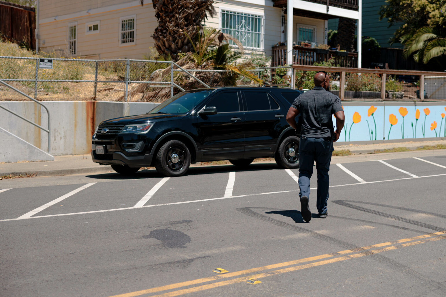 A Vallejo police detective walks back to his vehicle, a black American-made SUV, during daytime.