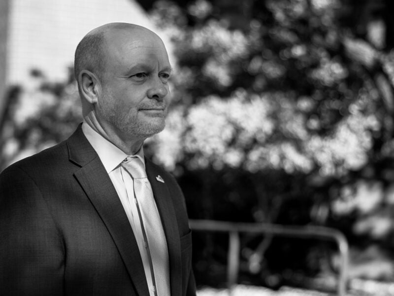 A black-and-white portrait of Andrew Murray in an outdoor setting, dressed in a formal suit and tie, looking off into the distance with a composed expression.