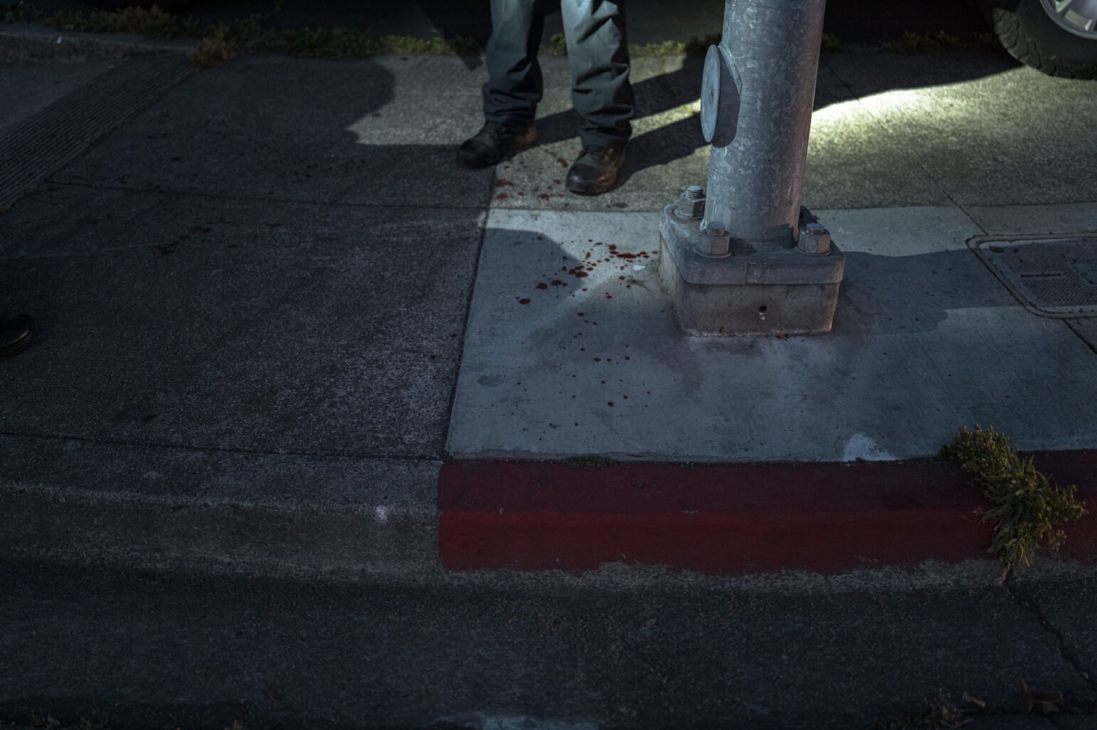 At dusk Dark Blood blow the concrete around the basis of a metal road light stick, while the investigators' boots is near the jet of the flashlight nearby.