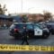 A Vallejo police officer wearing a helmet and carrying a rifle walks past police SUVs as the sun sets in Vallejo, California. Crime scene tape can be seen in the foreground.
