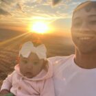 A young man holding a baby at sunset