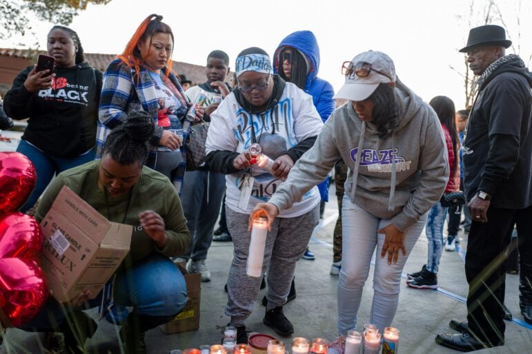 A group of people light votive candles in a drive-through outdoors.