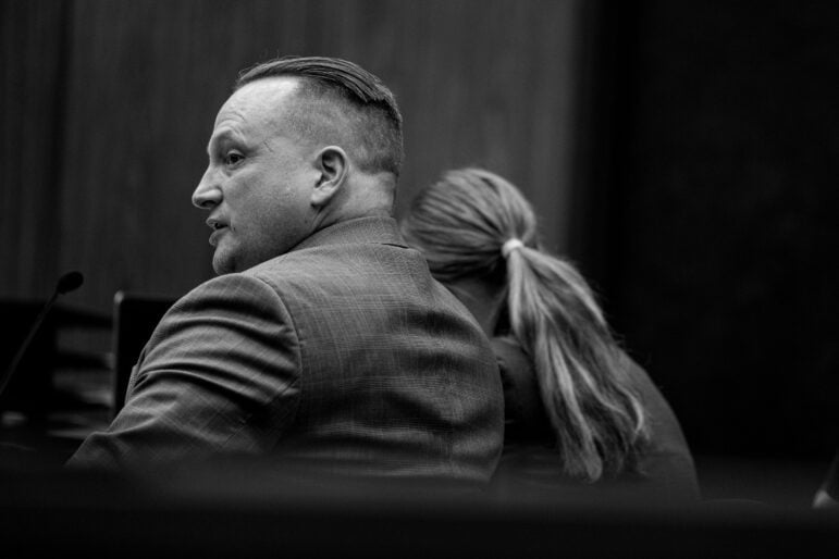 A white male lawyer in his 40s or 50s with an undercut haircut sitting in a courtroom.