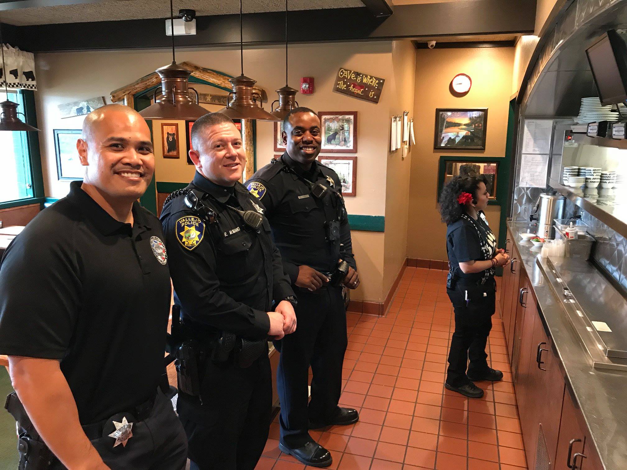 Three Vallejo police officers stand at a kitchen counter waiting to take orders to diners during a "tip-a-cop" charity event benefitting the Special Olympics of Northern California.