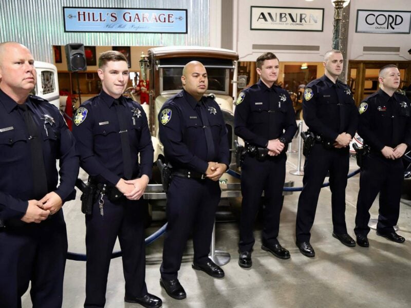 Six police officers stand at attention in an automotive museum