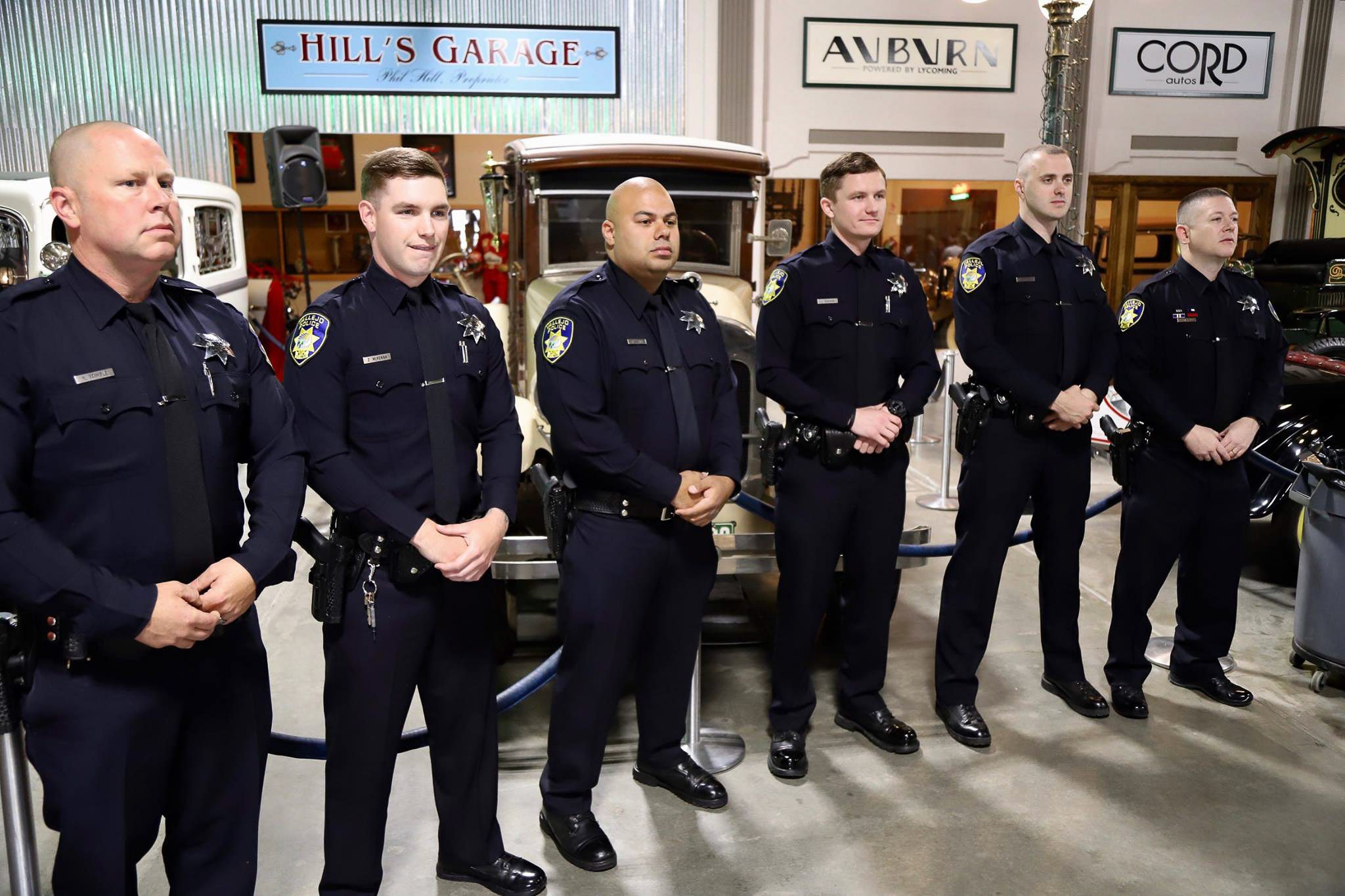 Six police officers stand at attention in an automotive museum