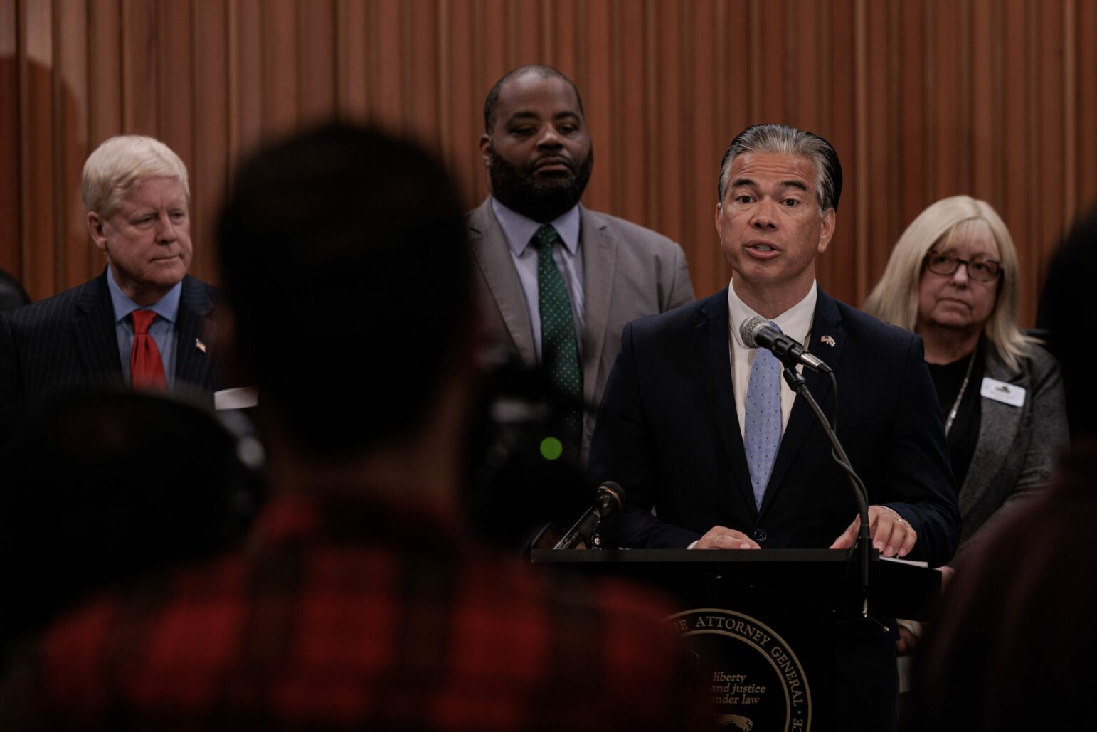 California Attorney General Rob Bonta speaks to reporters at a lectern inside Vallejo City Hall while surrounded by Vallejo officials and members of his senior leadership team.