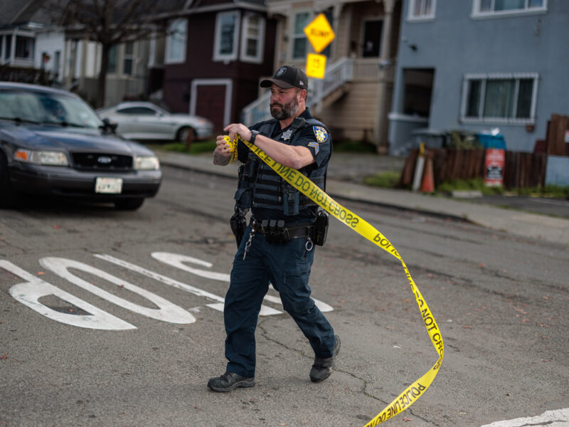 A Vallejo police corporal winds up crime scene tape during daytime.