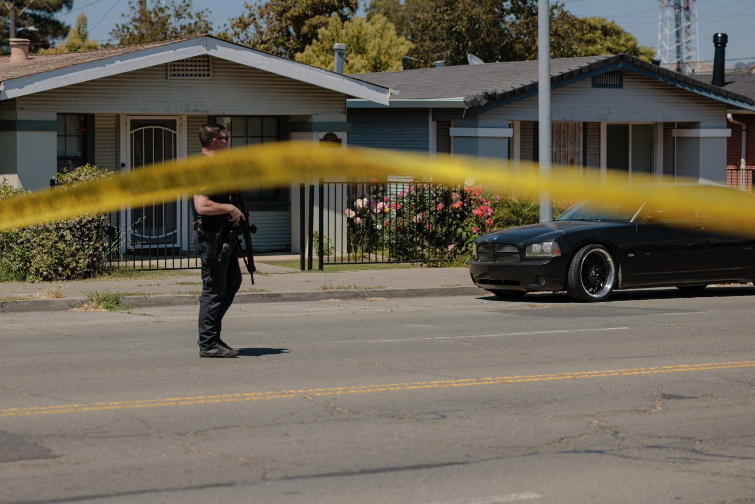 A Vallejo police officer walks down the street holding a rifle during daytime.