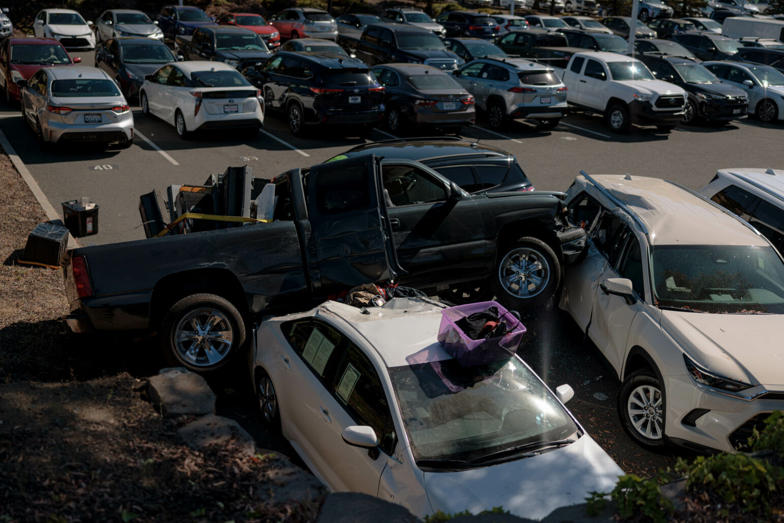 A crashed truck atop damaged cars.