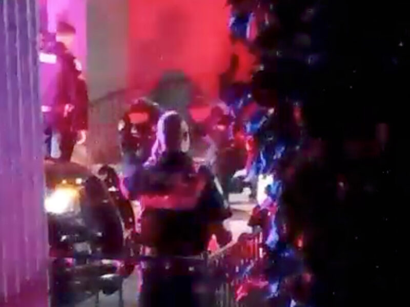 Vallejo police, lit by red and blue lights, attend to a young shooting victim at night.