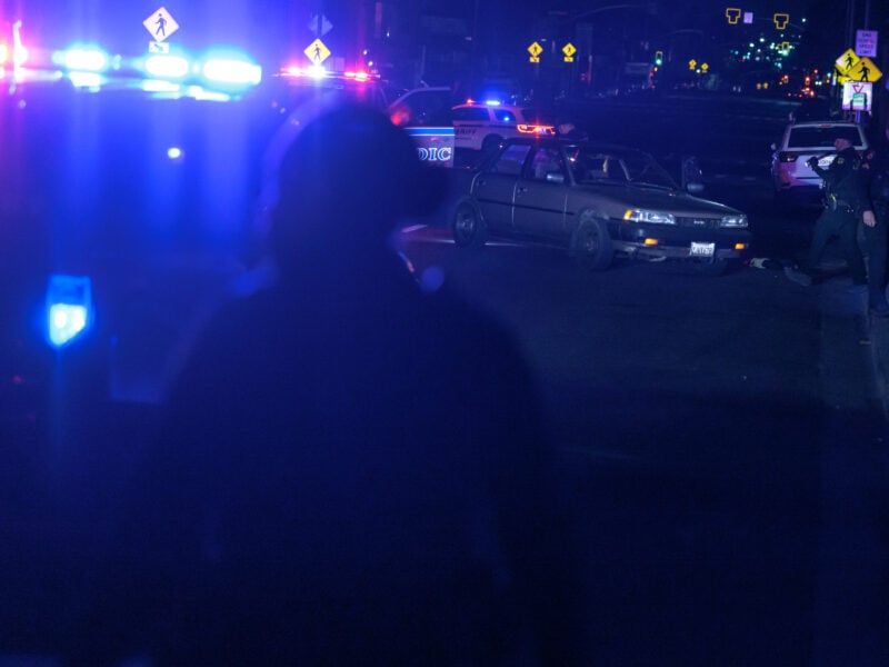 A sedan sits unoccupied among flash police lights as Vallejo police and Solano County Sheriff's deputies search for evidence of a shooting at night.