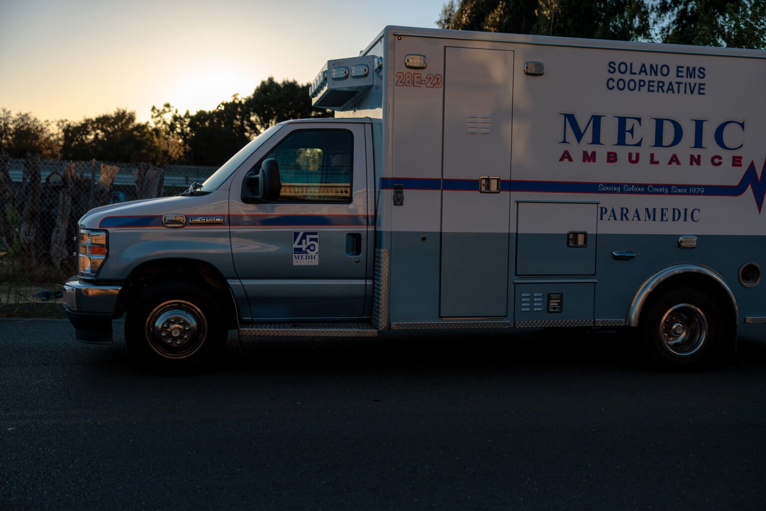 A Solano EMS Medic Ambulance is parked on a street at sunset. The logo and text on the side of the vehicle indicate that it is part of the Solano County Emergency Medical Services Cooperative.