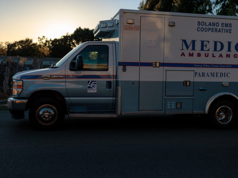 A Solano EMS Medic Ambulance is parked on a street at sunset. The logo and text on the side of the vehicle indicate that it is part of the Solano County Emergency Medical Services Cooperative.