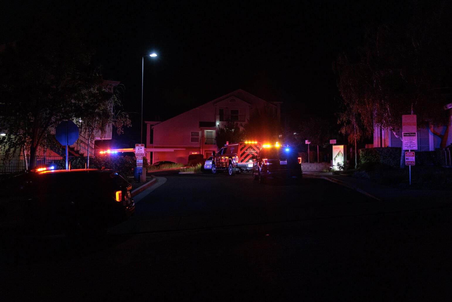 Vallejo police SUVs and a fire truck with their lights on at night.