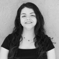 A professional black and white portrait of a smiling woman with dark hair and a dark top against a neutral background.