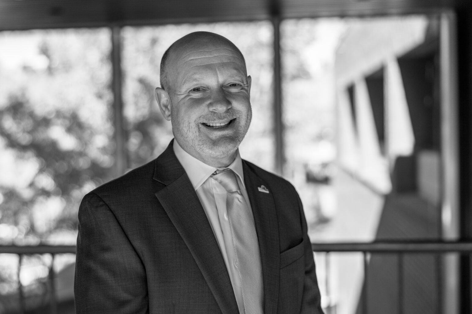 A black-and-white portrait of Andrew Murray standing in front of a window. He is smiling and dressed in formal attire, with trees visible through the window behind him.