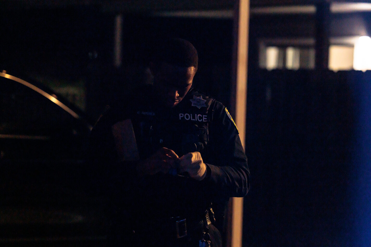 A Vallejo police officer examines evidence in low light during a nighttime investigation.