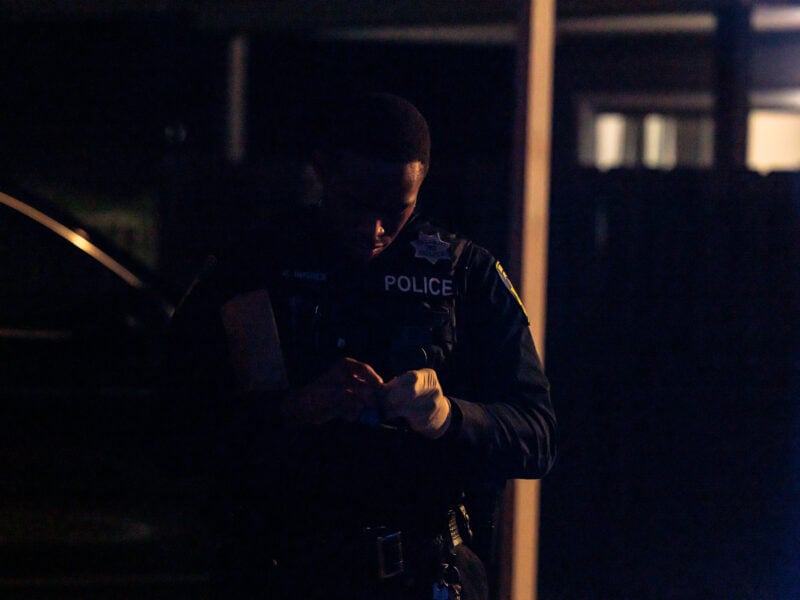 A Vallejo police officer examines evidence in low light during a nighttime investigation.