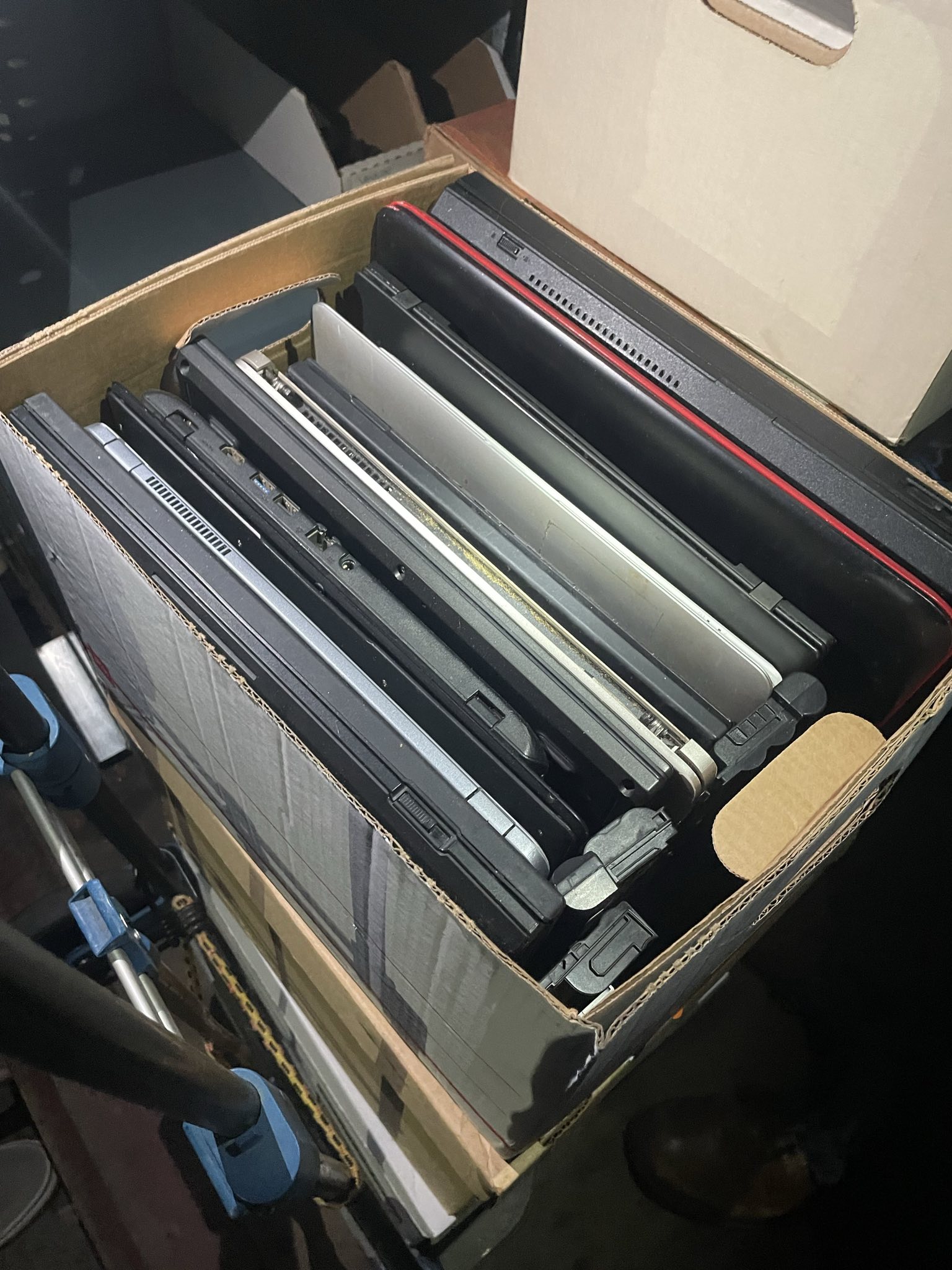 Thought about uniformed Border Patrol agent for a couple of seconds A cardboard box filled with multiple laptop computers of various models and colors, all standing on their sides in a neat row. The photo is taken from above, showing the edges and ports of the laptops stacked closely together in the box.