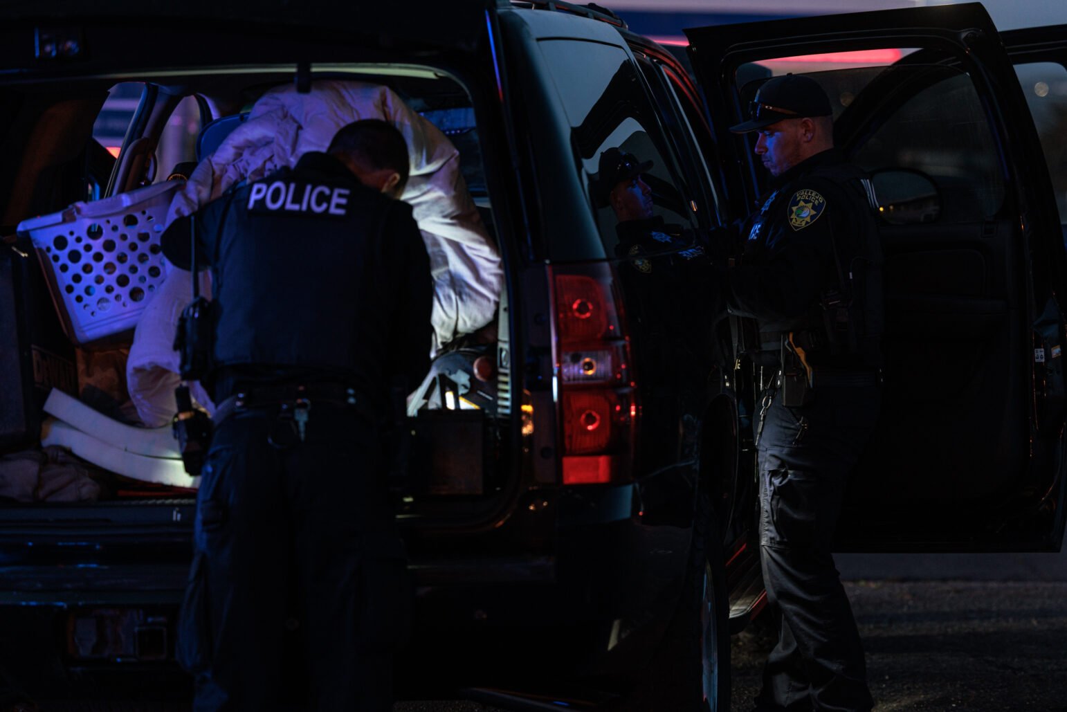 Two police officers from Vallejo search an overcrowded SUV at night - a marked 