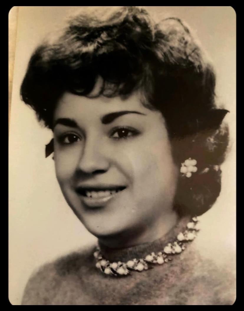 A formal black-and-white studio portrait of a young Evangelina R. Humphrey wearing a dark top and a floral necklace, smiling gently at the camera.