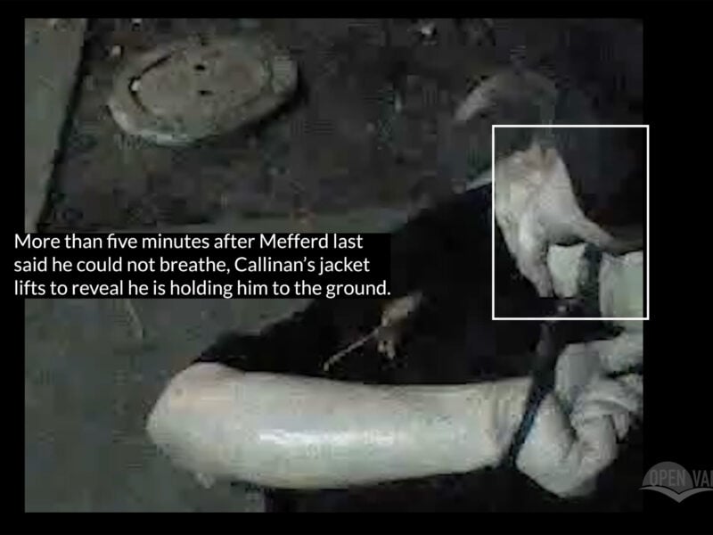 A dimly lit video still shows a man restrained on the ground with another person's hand gripping his arm. A caption overlays the image, stating that more than five minutes after Darryl Mefferd said he could not breathe, Officer Callinan’s jacket lifts, revealing he is holding Mefferd down. A white box highlights the officer’s hand. The Open Vallejo logo appears in the corner.