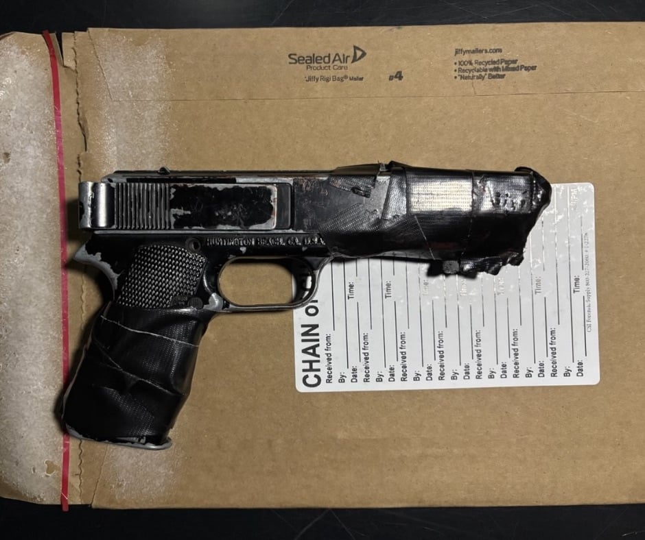 A black pellet gun wrapped in black tape on top of a police evidence envelope.