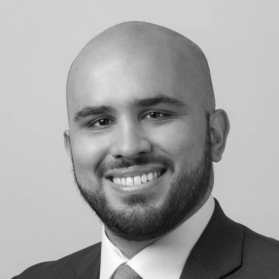 A professional, black and white headshot of a man in a suit and tie